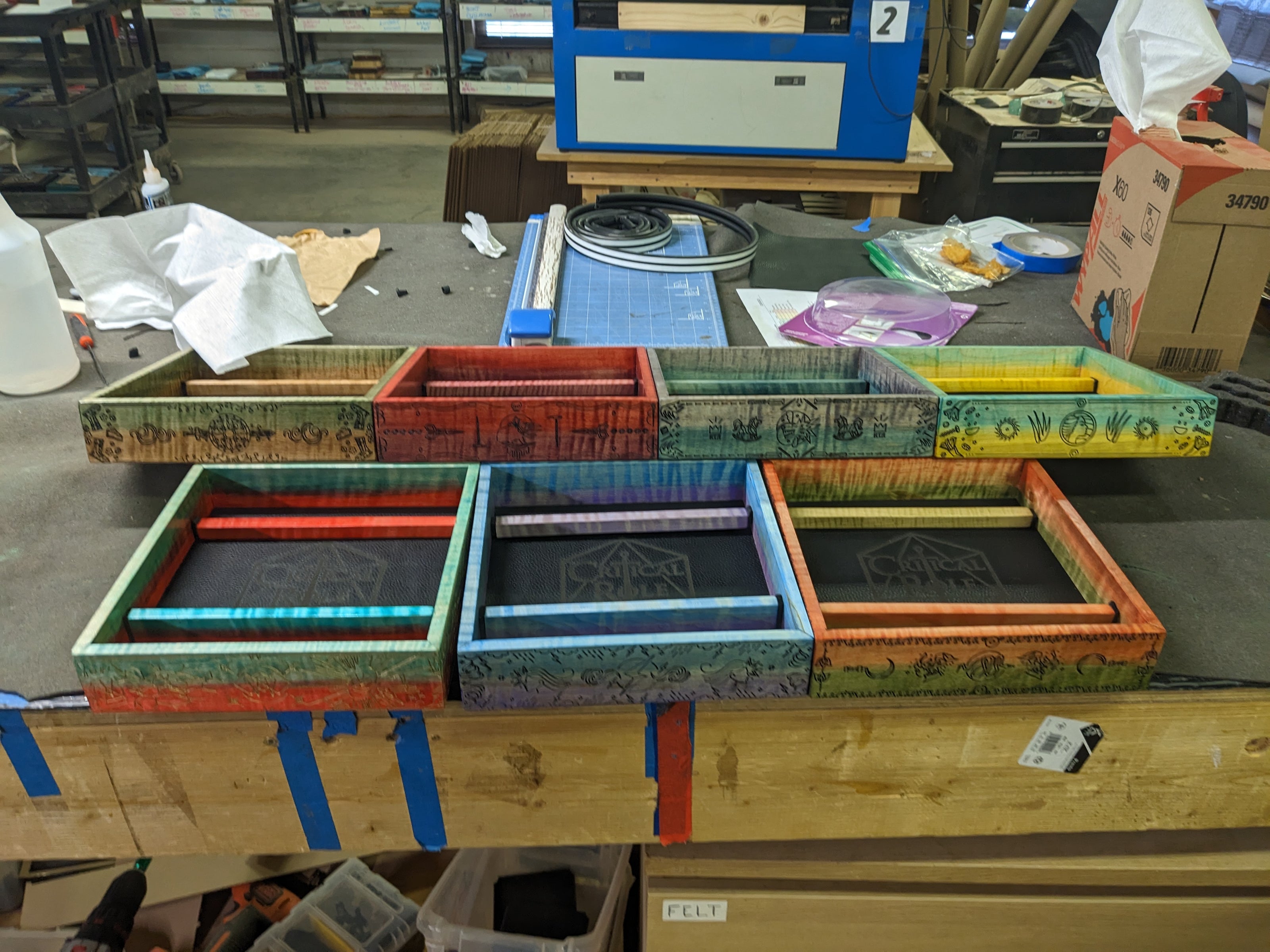 Colorful wooden trays on a table with various items in a workshop setting for Critical Role Live Stream