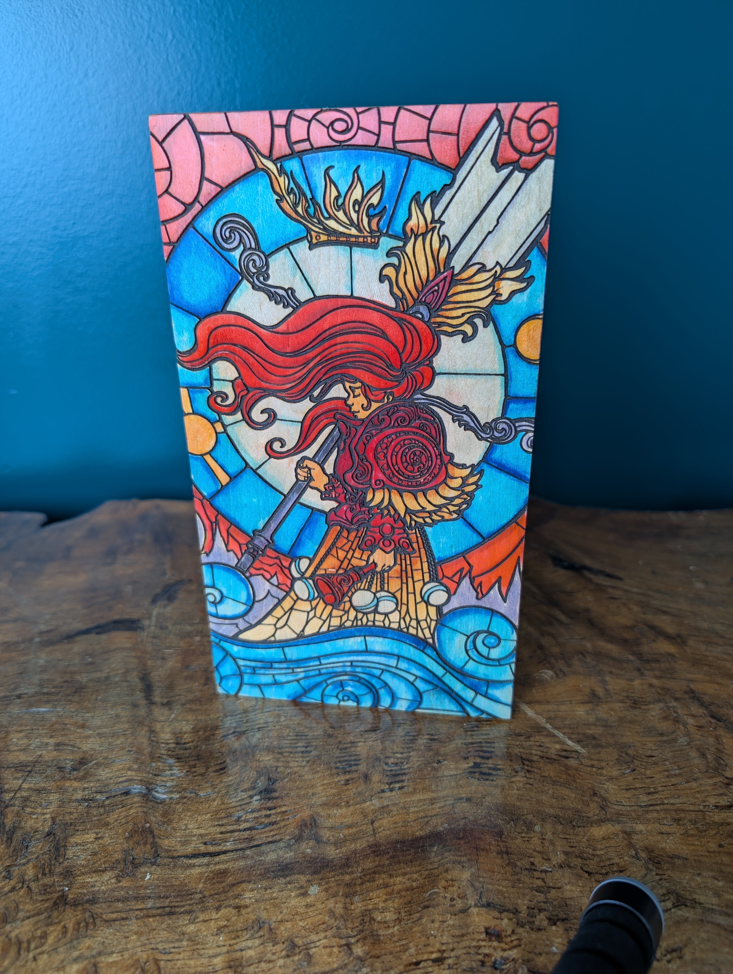 Colorful stained glass-style artwork of a warrior with red hair on a wooden surface.